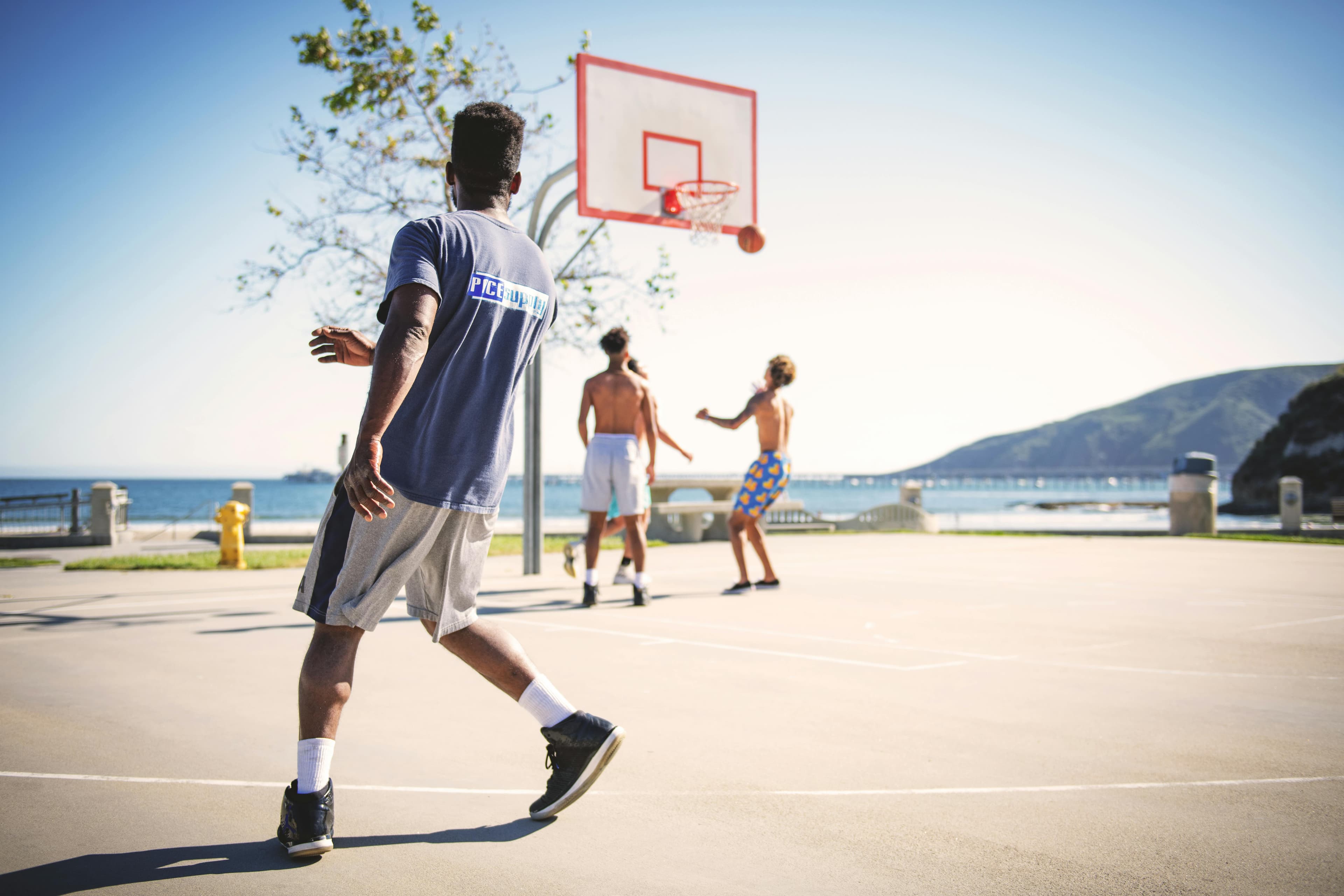 Friends playing basketball near the beach